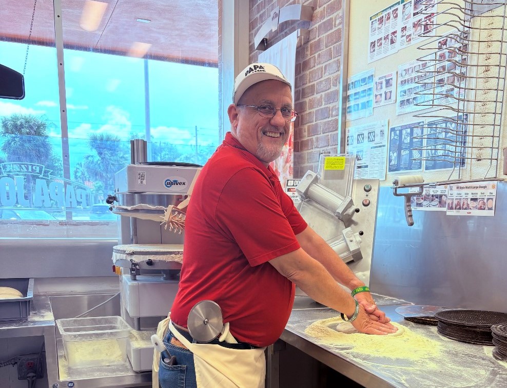 A man making a pizza inside a Papa Johns restaurant