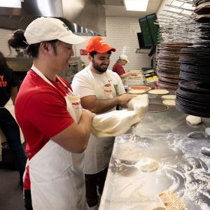 Papa Johns team member rolling dough