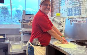 A man making a pizza inside a Papa Johns restaurant