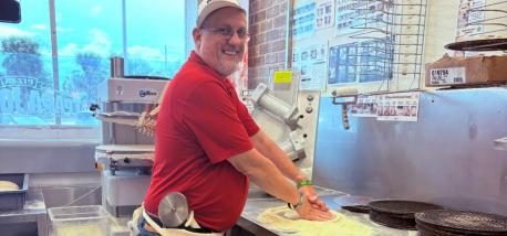 A man making a pizza inside a Papa Johns restaurant