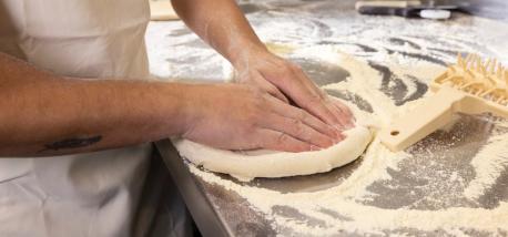 A person's hands preparing a pizza